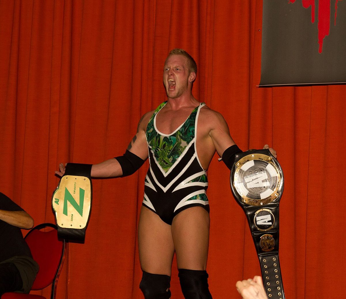 Josh Alexander with the two singles title belts for Alpha-1 wrestling: the Alpha Male championship in his left hand, and the Zero Gravity ch