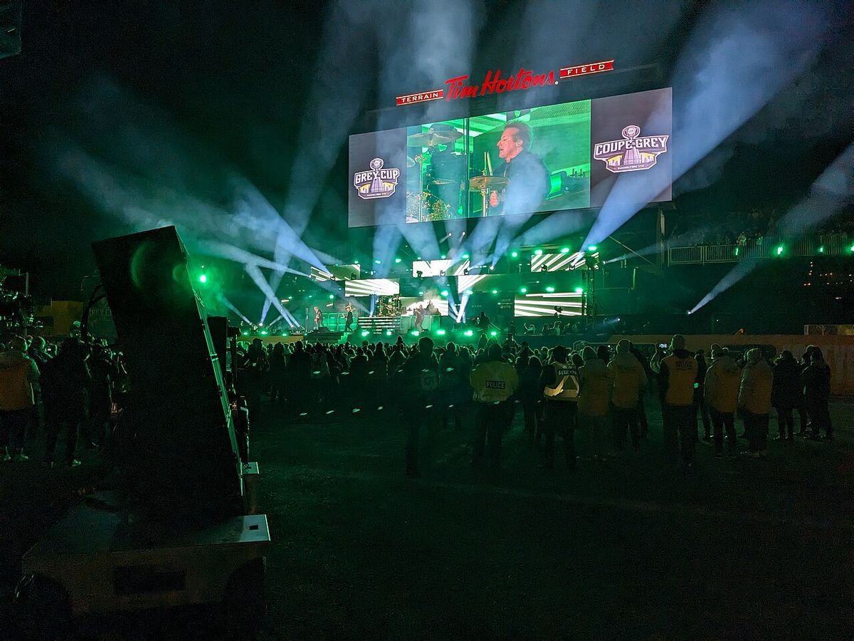 Green Day playing at Tim Hortons Field in Hamilton Ontario. Drummer Tré Cool is on the end zone video screen as the band plays.